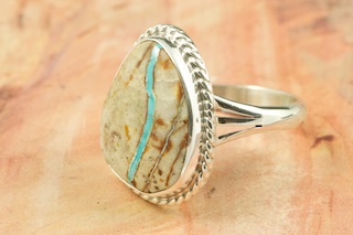 Genuine Boulder Turquoise set in Sterling Silver Ring. The cabachon is Boulder Turquoise, you can see the veins of Turquoise running through the host rock. The Boulder Turquoise Mine is located in northeast Nevada. It was discovered in 1970 by a Shoshone sheep herder. Production is small due to the remote location and winter weather. Boulder Turquoise is valued for both it's beauty and rarity. Every stone is unique. Created by Navajo Artist Tony Garcia. Signed.